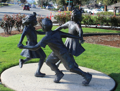 Sculpture of 2 girls and a boy at play